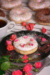 Delicious donuts, flowers and cup of coffee, closeup