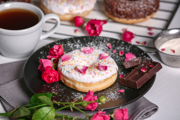 Delicious donuts, flowers and cup of coffee, closeup