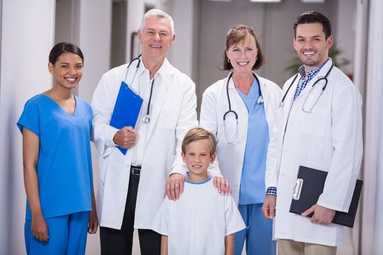 Doctors and nurse standing with boy patient in hospital corridor