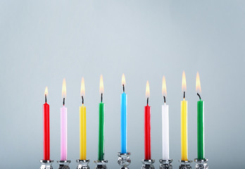 Menorah with colorful candles for Hanukkah on light background, close up