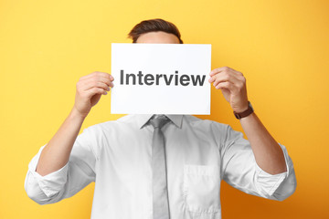 Young man posing with paper on yellow background