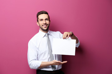 Young man posing with paper on pink background