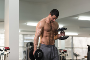 Fototapeta na wymiar Biceps Exercise With Dumbbell in a Gym