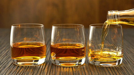 Pouring whiskey into the glass on a wooden table