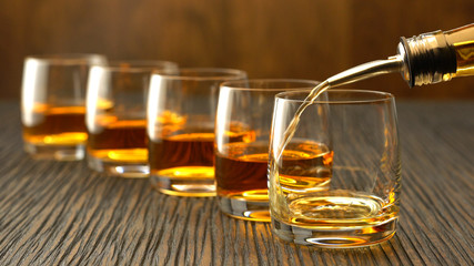 Pouring whiskey into the glass on a wooden table