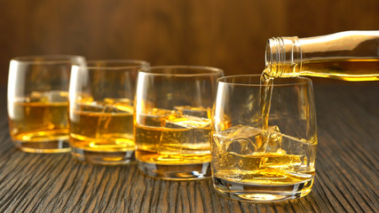 Pouring whiskey into the glass on a wooden table