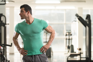 Fototapeta na wymiar Strong Man in Green T-shirt Background Gym