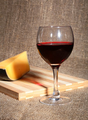 Still life with red wine grapes and chees on wooden table.