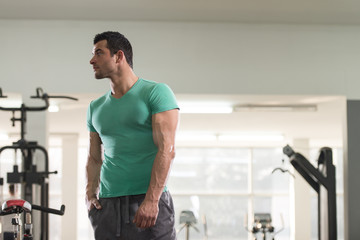 Obraz na płótnie Canvas Strong Man in Green T-shirt Background Gym