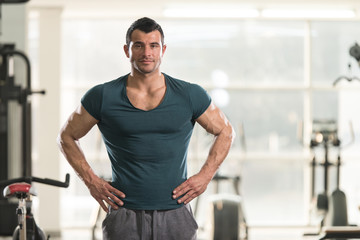 Fototapeta na wymiar Strong Man in Green T-shirt Background Gym
