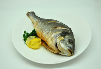 fried carp fish with lemon and parsley on a white background