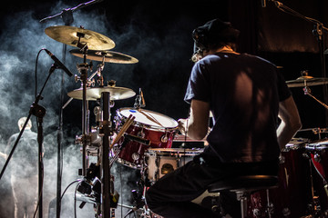 Batterista suona sul palco assolo di batteria durante il concerto, effetto fumo e luci. - obrazy, fototapety, plakaty