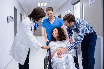 Man and doctors consoling pregnant woman in corridor