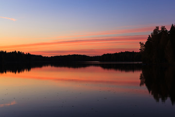 Obraz premium Serene view of calm lake and sunset clouds
