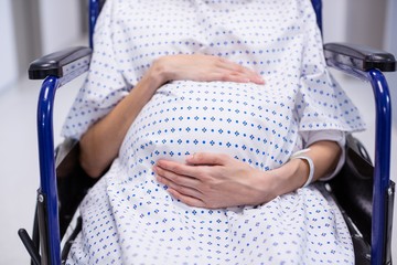 Mid section of pregnant woman sitting on wheelchair