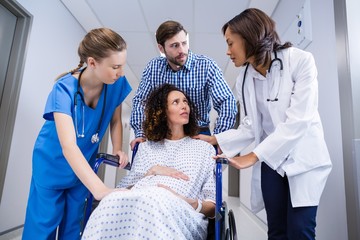 Doctors and man comforting pregnant woman in corridor