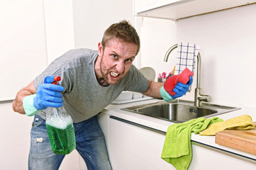 young man holding cleaning detergent spray and sponge washing home kitchen clean angry in stress