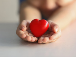 Fototapeta premium Child holding small red heart, closeup. Adoption concept