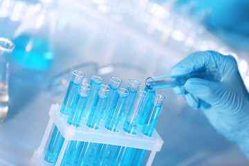 Hand in glove pouring a sample into a  test tube, closeup
