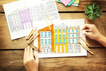 Obraz premium Woman sitting at table with coloring pictures for adults, closeup