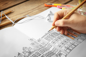 Woman sitting at table with coloring book for adults, closeup