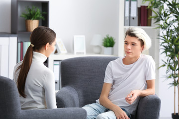 Young female psychologist working with teenager boy in office