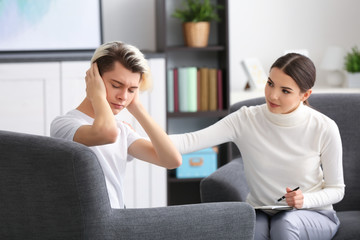 Young female psychologist working with teenager boy in office
