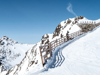 Fence shielding slope in winter mountain panorama on sunny day
