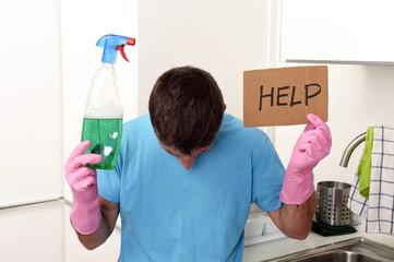 messy man in stress in washing gloves holding detergent spray bottle asking for help