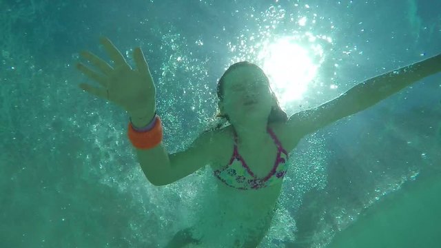 View from the water on the sun's rays. Beautiful girl dives into the water