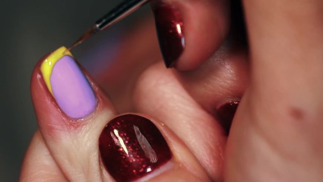 Manicure procedure female hand drawing yellow emoji on white finger nail polish, close up