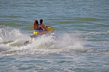 Two young women riding tandem on a high speed jet ski.
