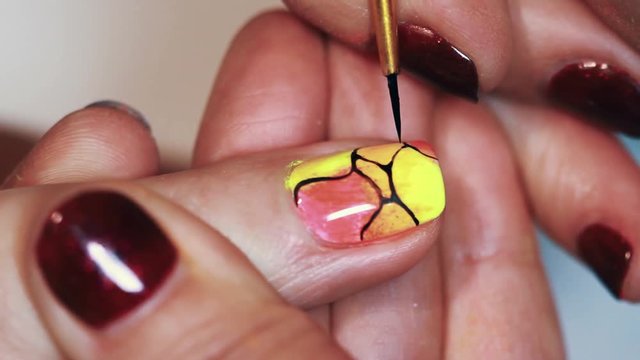 Manicurist woman painting abstract pattern on colorful nail polish beauty shop, close up