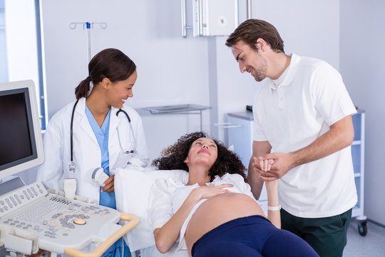 Man comforting pregnant woman during ultrasound