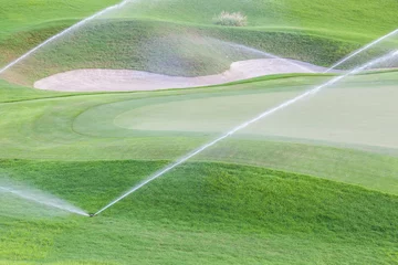 Sprinkler-Bewässerungssystem, das auf einem grünen Golfplatz arbeitet. © mrcmos