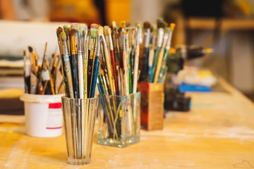 Paint Brushes in vase on a wooden table, close-up