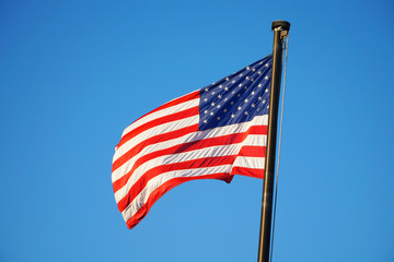 waving USA flag on pole against blue sky