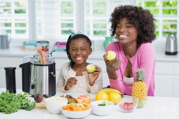 Smiling mother and daughter preparing smoothie 