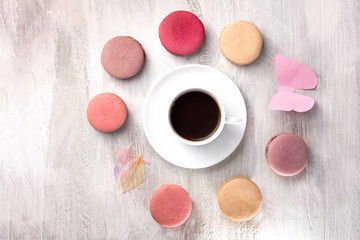 Cup of coffee with macarons and paper butterfly
