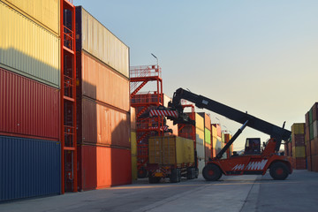 Container handling, reach stacker  lift off container from trailer inside container yard. Container logistics concept.