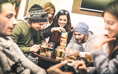 Happy friends playing table board game while drinking beer at pub - Cheerful people having fun at...