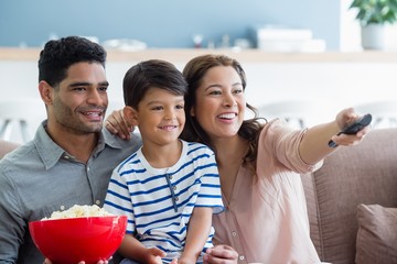 Parents and son watching television in living room