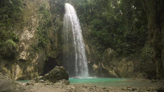 Waterfall in green forest in jungle. Beautiful waterfall in the mountains. Tropical rain forest with waterfall. Philippines, Cebu. 4K video. Travel concept.