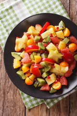 Natural Food: Salad of fresh exotic tropical fruits close-up on a plate. vertical top view