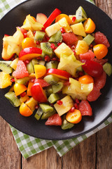 Natural Food: Salad of fresh exotic tropical fruits macro on a plate. vertical top view