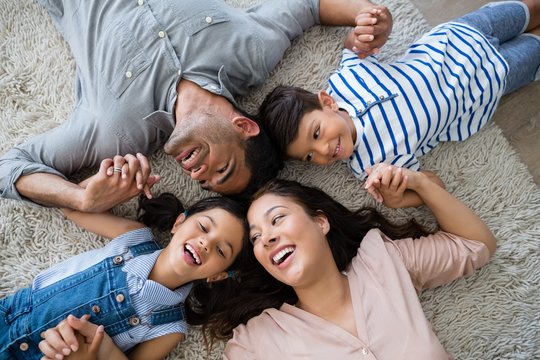 Happy family interacting while lying on rug