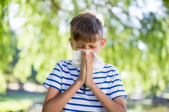 Boy wiping his nose while sneezing