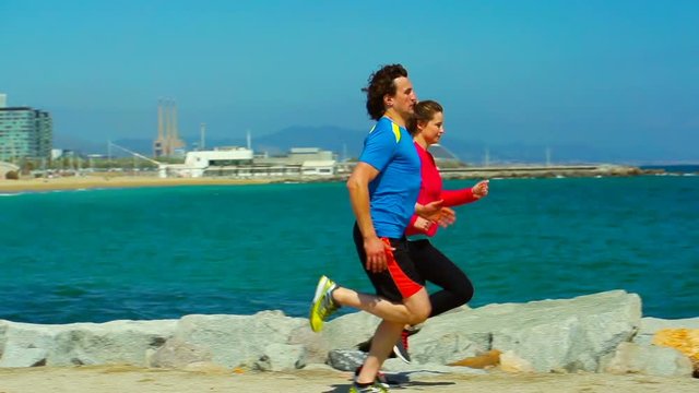 Couple running next to the navy blye sea, steadycam shot, slow motion shot at 240fps
