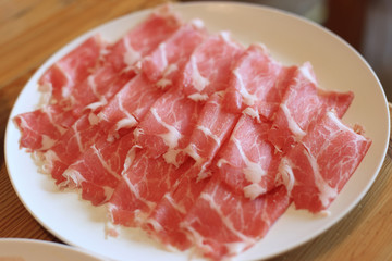 Raw pork sliced in white dish for shabushabu, Japanese recipe.