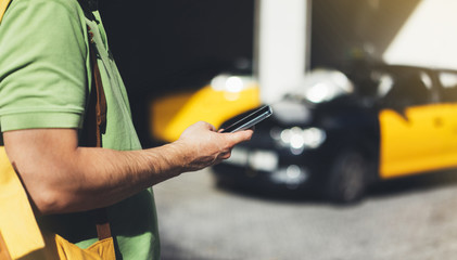 Man pointing finger on screen smartphone on background yellow taxi, tourist hipster using in hands...